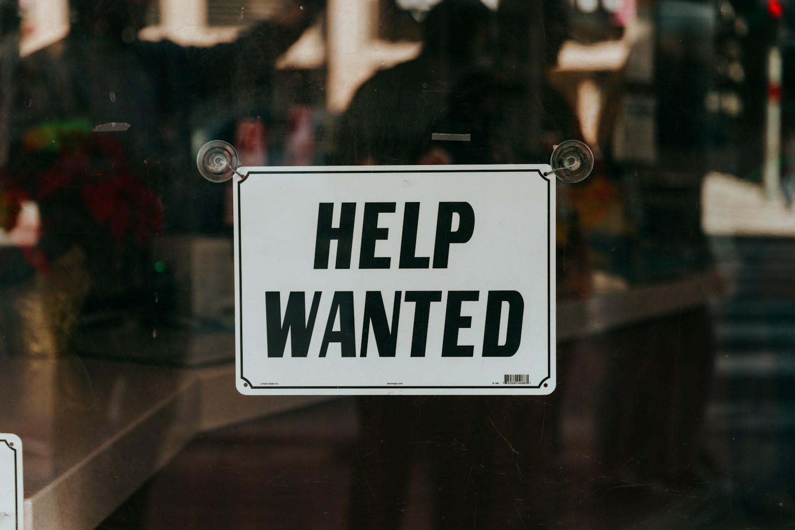 a sign that says help wanted on a glass door. Counselling for unemployed workers is more important than ever