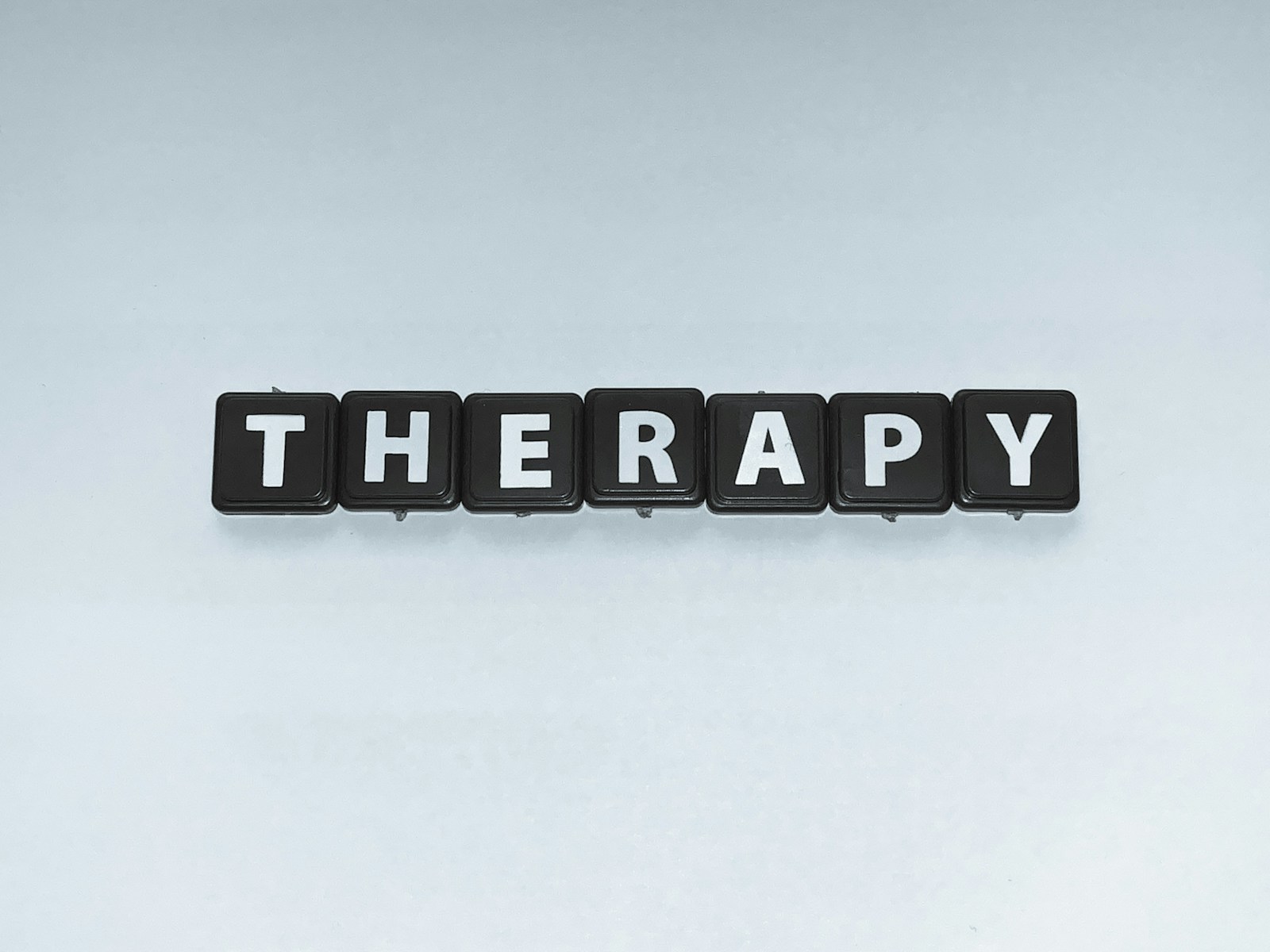 The word "Therapy" in scrabble tiles. This article explore EMDR therapy, what is EMDR therapy? How does EMDR therapy work? How can EMDR therapy help?